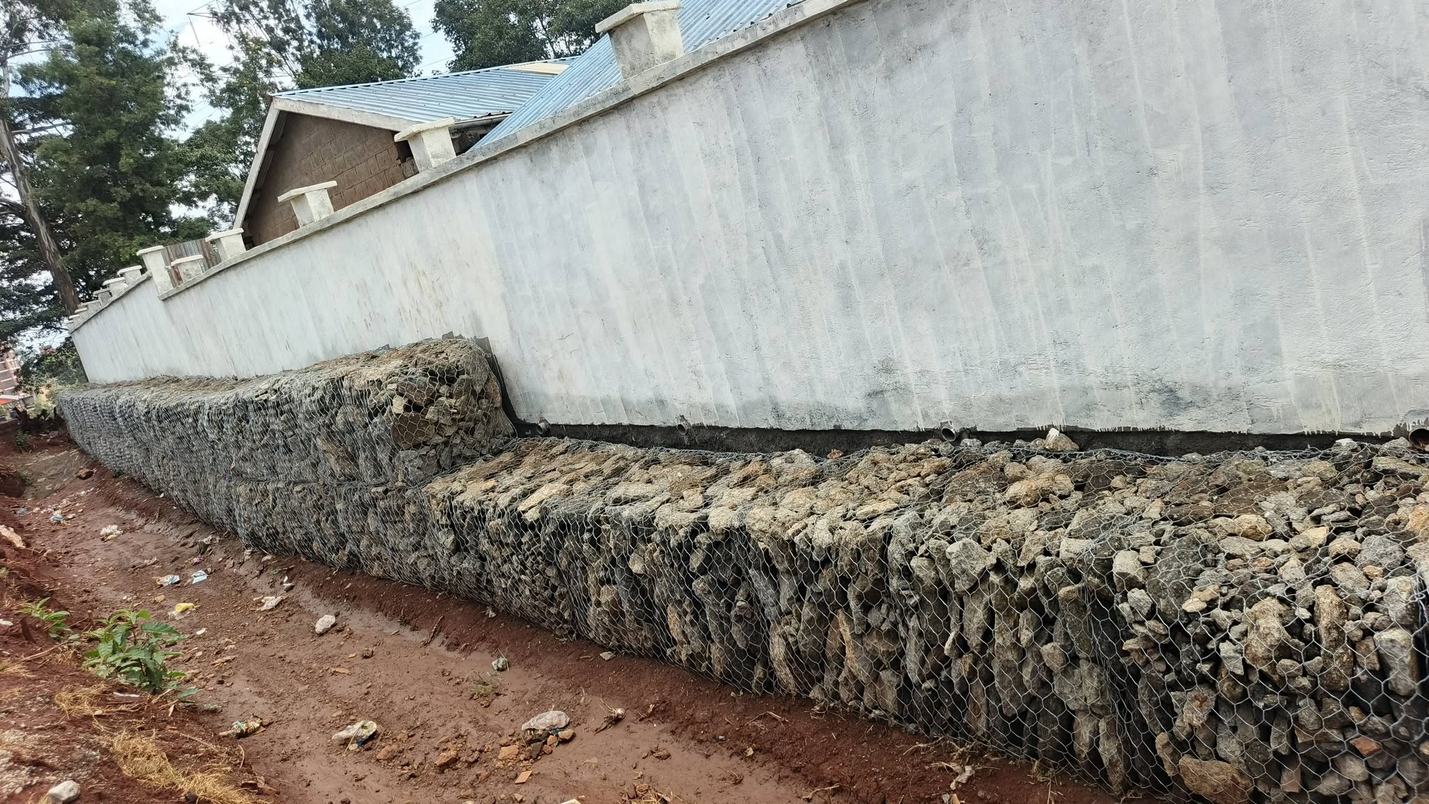 Long gabion retaining wall beside a boundary wall